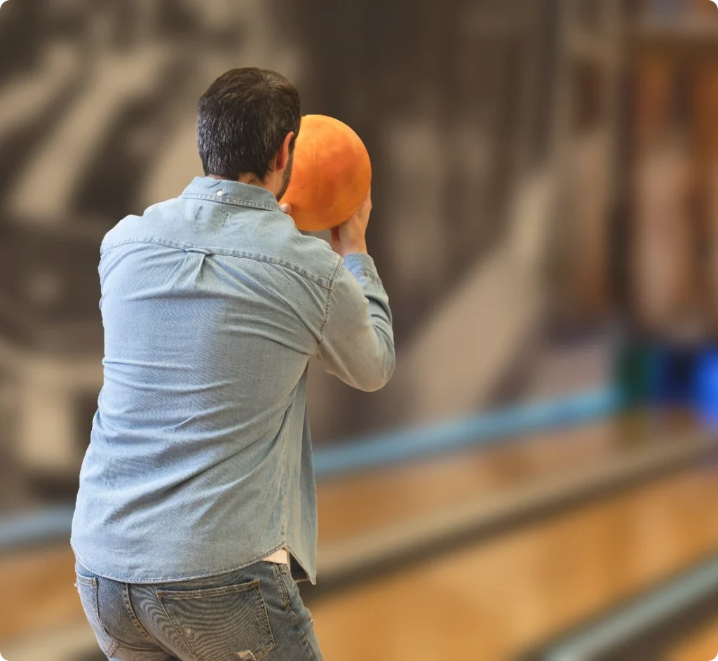 Man kastar orange bowlingklot på banan
